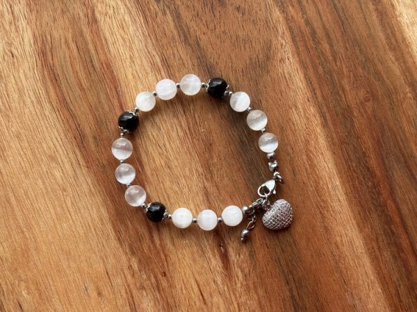 Pulseira artesanal com cristais naturais Selenite, Turmalina Negra e Hematite. Inclui pendente em forma de coração com zircónias brancas. Criação com intenção para proteção energética, foco emocional e paz interior.