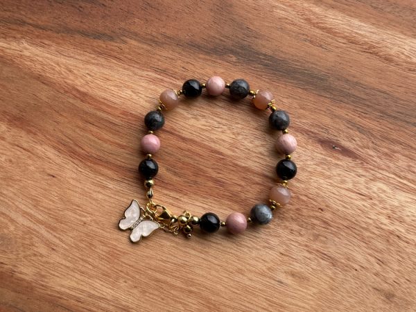 Pulseira feminina artesanal com cristais Obsidiana, Pedra da Lua Pêssego, Labradorite, Rodonite e Hematite. Inclui pendente borboleta em madrepérola com micro zircónias. Criação com intenção para transformação emocional, proteção e intuição.