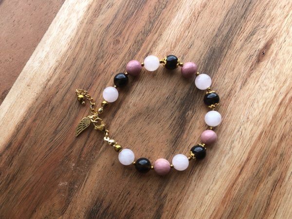 Pulseira artesanal feminina com cristais Quartzo Rosa, Quartzo Fumaçado, Rodonite e Hematite. Inclui pendente Asa de Anjo. Criação com intenção para amor-próprio, proteção emocional e estabilidade interior.